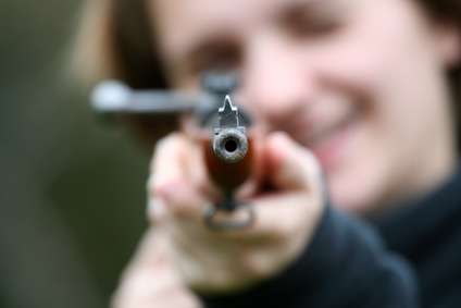 Mann schießt mit Luftgewehr auf Schüler Verschwommene Person zielt mit einem Luftgewehr in die Kamera